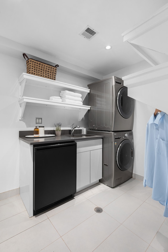 laundry room with light tile patterned floors, visible vents, recessed lighting, a sink, and stacked washer and dryer