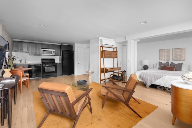 bedroom featuring light wood-type flooring, a wall unit AC, and freestanding refrigerator