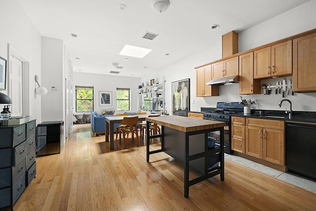 kitchen with visible vents, a sink, black appliances, under cabinet range hood, and light wood-type flooring