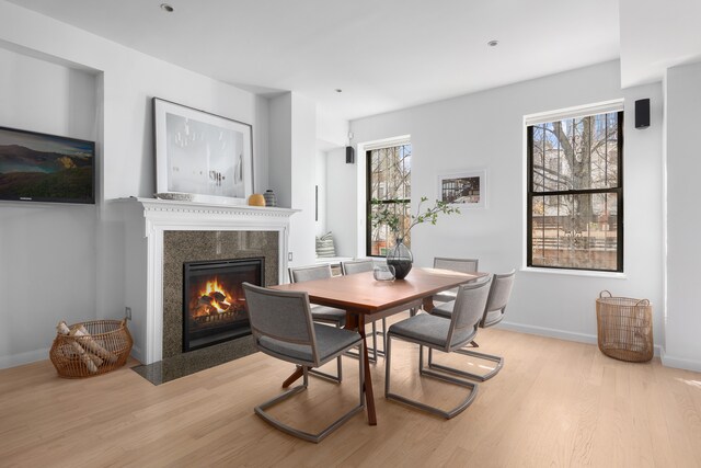 dining area featuring wood finished floors, a fireplace, and baseboards