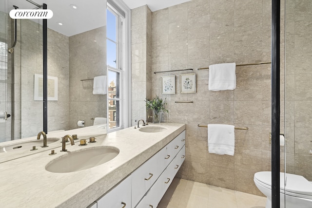 bathroom featuring tile walls, toilet, healthy amount of natural light, double vanity, and tile patterned flooring