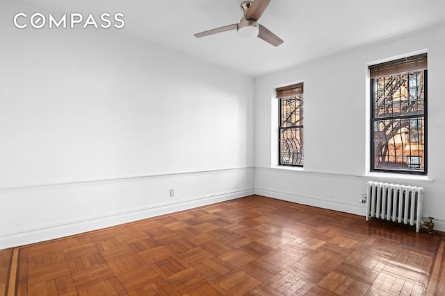 empty room featuring radiator heating unit, baseboards, and ceiling fan