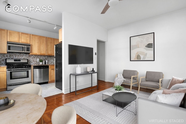 living area featuring baseboards and a ceiling fan