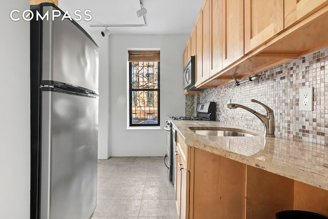 kitchen with a sink, backsplash, stainless steel appliances, light tile patterned flooring, and light stone countertops