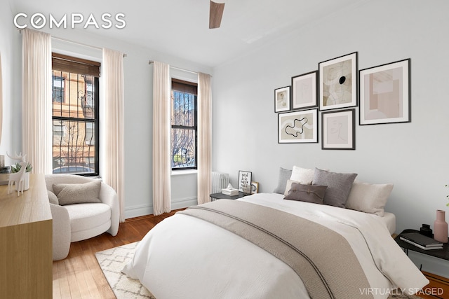 bedroom with radiator, baseboards, ceiling fan, and wood finished floors