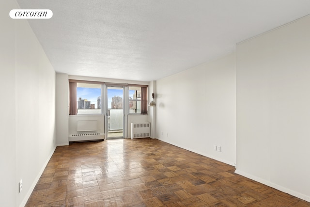 empty room with radiator, baseboards, visible vents, and a textured ceiling