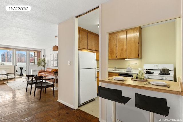 kitchen featuring visible vents, a textured ceiling, radiator heating unit, white appliances, and light countertops