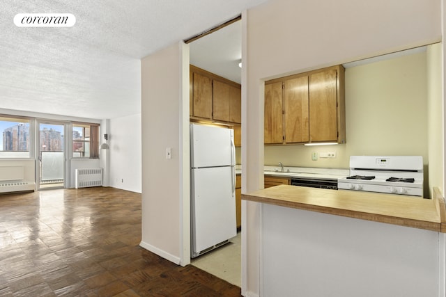 kitchen featuring visible vents, a textured ceiling, radiator heating unit, white appliances, and light countertops