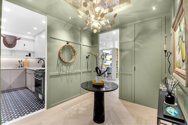 bathroom with a sink, a chandelier, recessed lighting, and a decorative wall