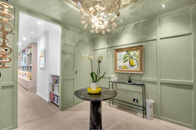 interior space featuring a chandelier, a decorative wall, and wood finished floors