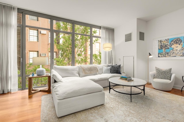 living area featuring light wood-style flooring, visible vents, and expansive windows