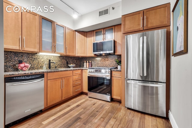 kitchen with visible vents, dark stone counters, decorative backsplash, appliances with stainless steel finishes, and a sink