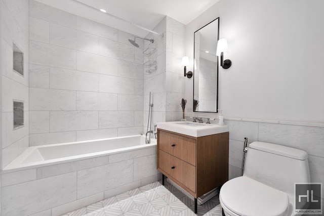 full bath with tiled shower / bath, a wainscoted wall, toilet, tile walls, and vanity