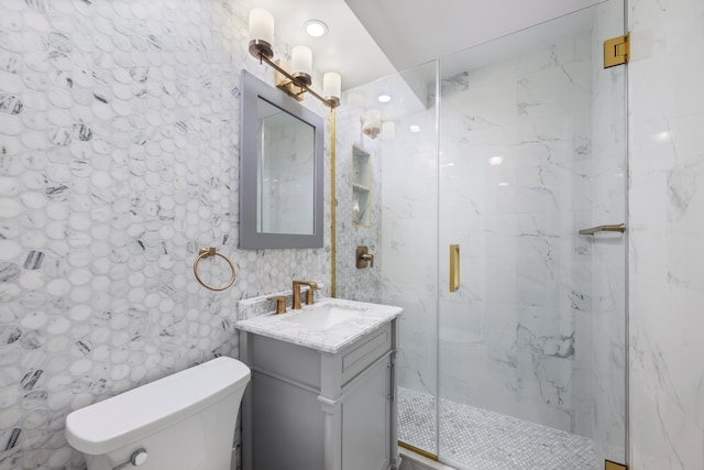 bathroom with a marble finish shower, toilet, vanity, recessed lighting, and tile walls