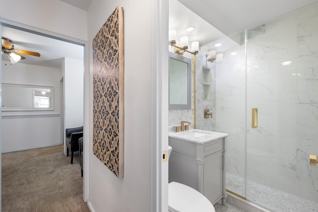 bathroom with a marble finish shower, toilet, ceiling fan, and vanity