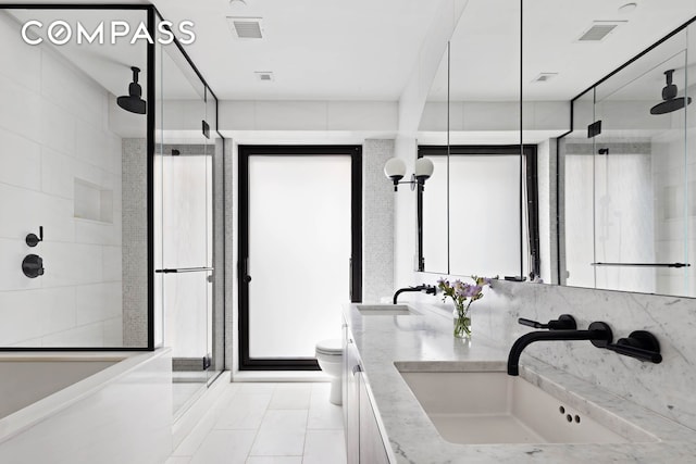 bathroom featuring a shower stall, toilet, and double vanity