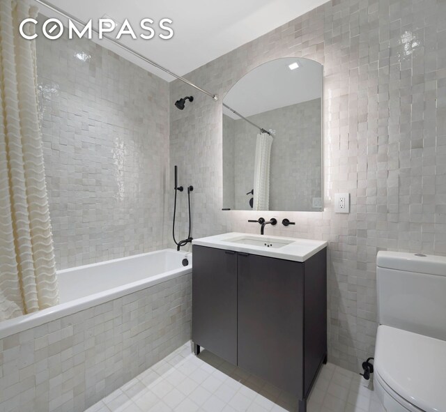 full bath featuring tile walls, tile patterned floors, tiled shower / bath, toilet, and vanity