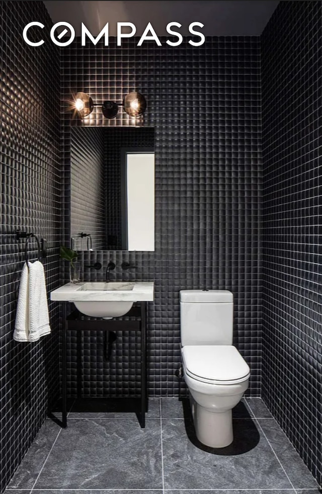 bathroom with toilet, tile walls, and tile patterned flooring