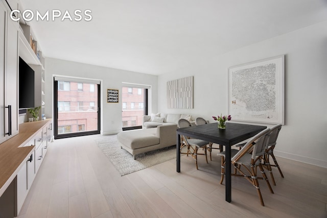 dining space featuring light wood finished floors and baseboards