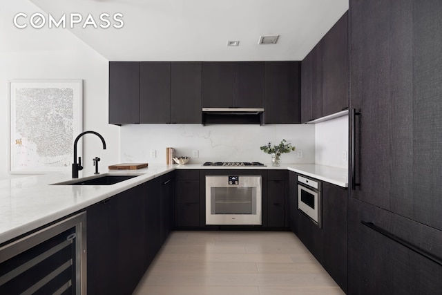 kitchen with oven, a sink, beverage cooler, and light countertops