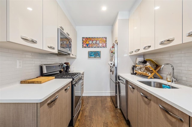 kitchen with dark wood finished floors, appliances with stainless steel finishes, light countertops, and a sink