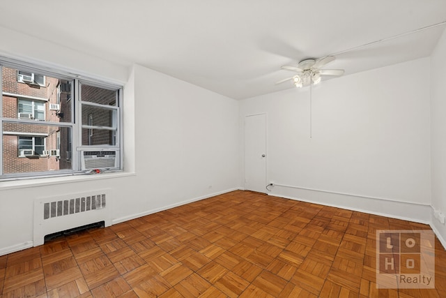 empty room featuring a ceiling fan, baseboards, and radiator