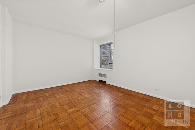 empty room featuring radiator heating unit and baseboards