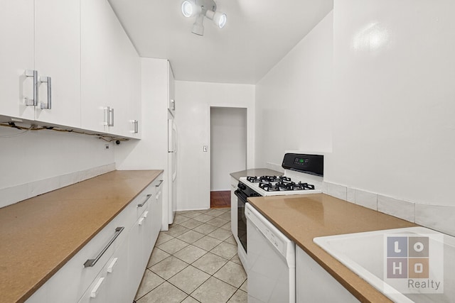 kitchen with light tile patterned flooring, white cabinets, and white appliances