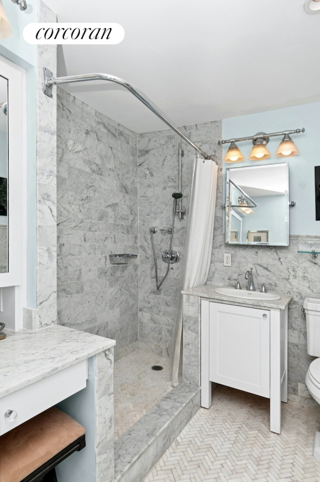 full bathroom featuring vanity, tile walls, toilet, and tiled shower