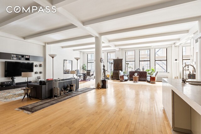 15 W 24th St Unit 3, New York City, NY 10010 - living area featuring beamed ceiling, radiator heating unit, and light wood-type flooring