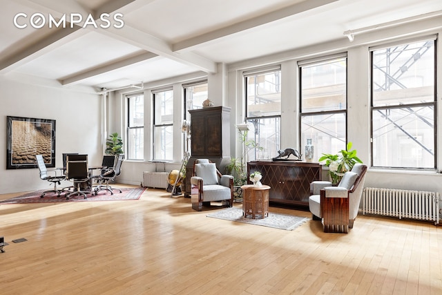 sitting room with beamed ceiling, wood-type flooring, radiator, and arched walkways