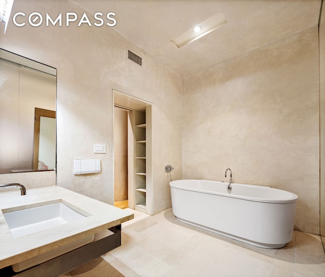 bathroom with a sink, visible vents, and a freestanding bath