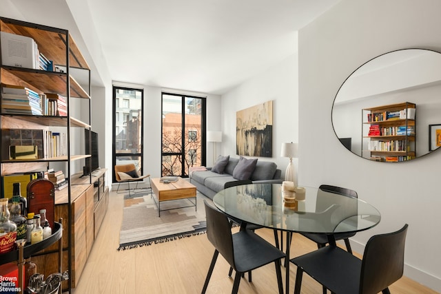 dining space with expansive windows, baseboards, and wood finished floors