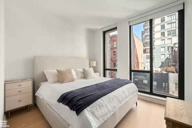 bedroom featuring expansive windows and light wood-style floors