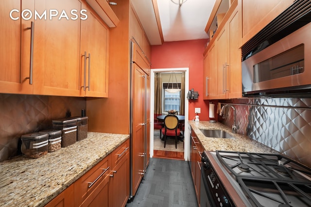 kitchen featuring backsplash, appliances with stainless steel finishes, light stone countertops, and a sink