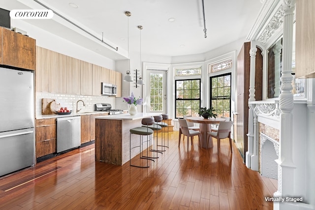 kitchen featuring a breakfast bar area, a kitchen island, light countertops, appliances with stainless steel finishes, and modern cabinets