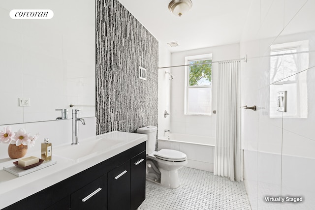 full bathroom with visible vents, toilet, vanity, shower / bath combo, and tile walls