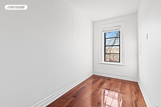 empty room featuring baseboards and dark wood-style floors