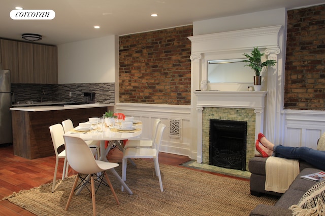 dining area with visible vents, a fireplace, wood finished floors, and a wainscoted wall