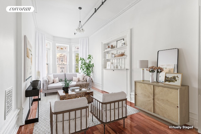 living area with visible vents, a notable chandelier, hardwood / wood-style floors, and ornamental molding