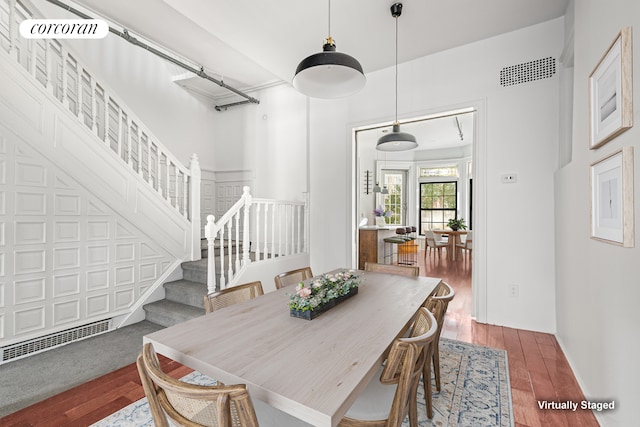 dining space featuring visible vents, baseboards, wood finished floors, and stairway