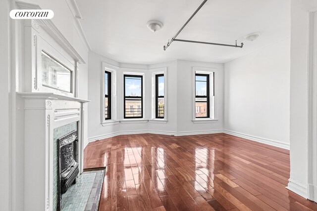 unfurnished living room featuring visible vents, crown molding, baseboards, a fireplace with flush hearth, and hardwood / wood-style floors