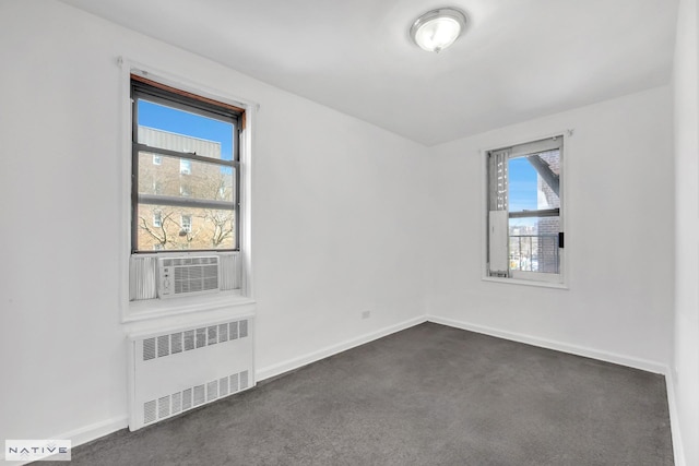 spare room featuring radiator, baseboards, and dark colored carpet