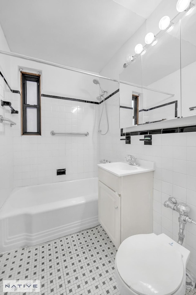 full bathroom featuring toilet, tile walls, vanity, and washtub / shower combination