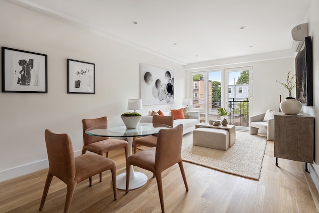 dining space featuring a wall mounted air conditioner, baseboards, and light wood-style floors