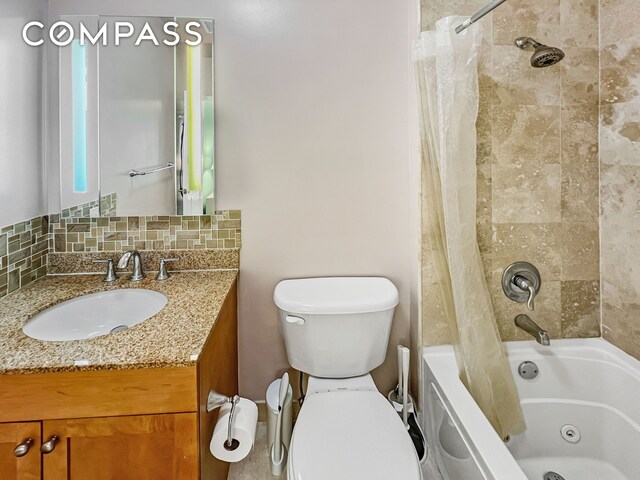 bathroom with tasteful backsplash, a combined bath / shower with jetted tub, vanity, and toilet