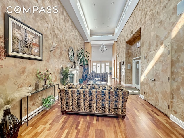 interior space featuring a notable chandelier, a tray ceiling, wood finished floors, baseboards, and a towering ceiling