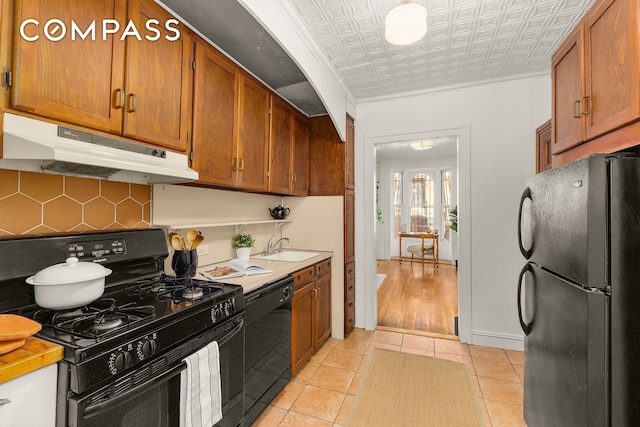 kitchen with brown cabinets, black appliances, under cabinet range hood, an ornate ceiling, and decorative backsplash