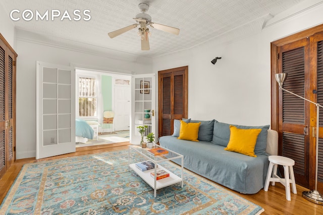 living room with crown molding, wood finished floors, an ornate ceiling, and ceiling fan