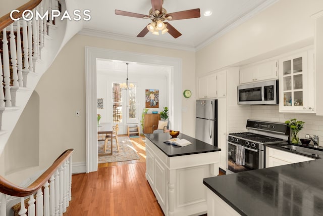 kitchen with dark countertops, ornamental molding, appliances with stainless steel finishes, and a sink